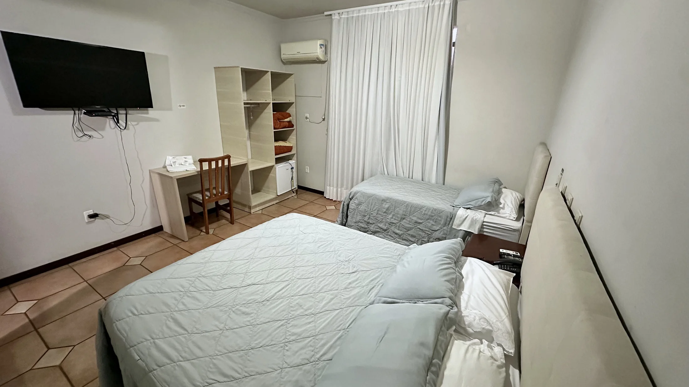 Quarto do Hotel Beira Rio com camas, TV, mesa, armário e frigobar