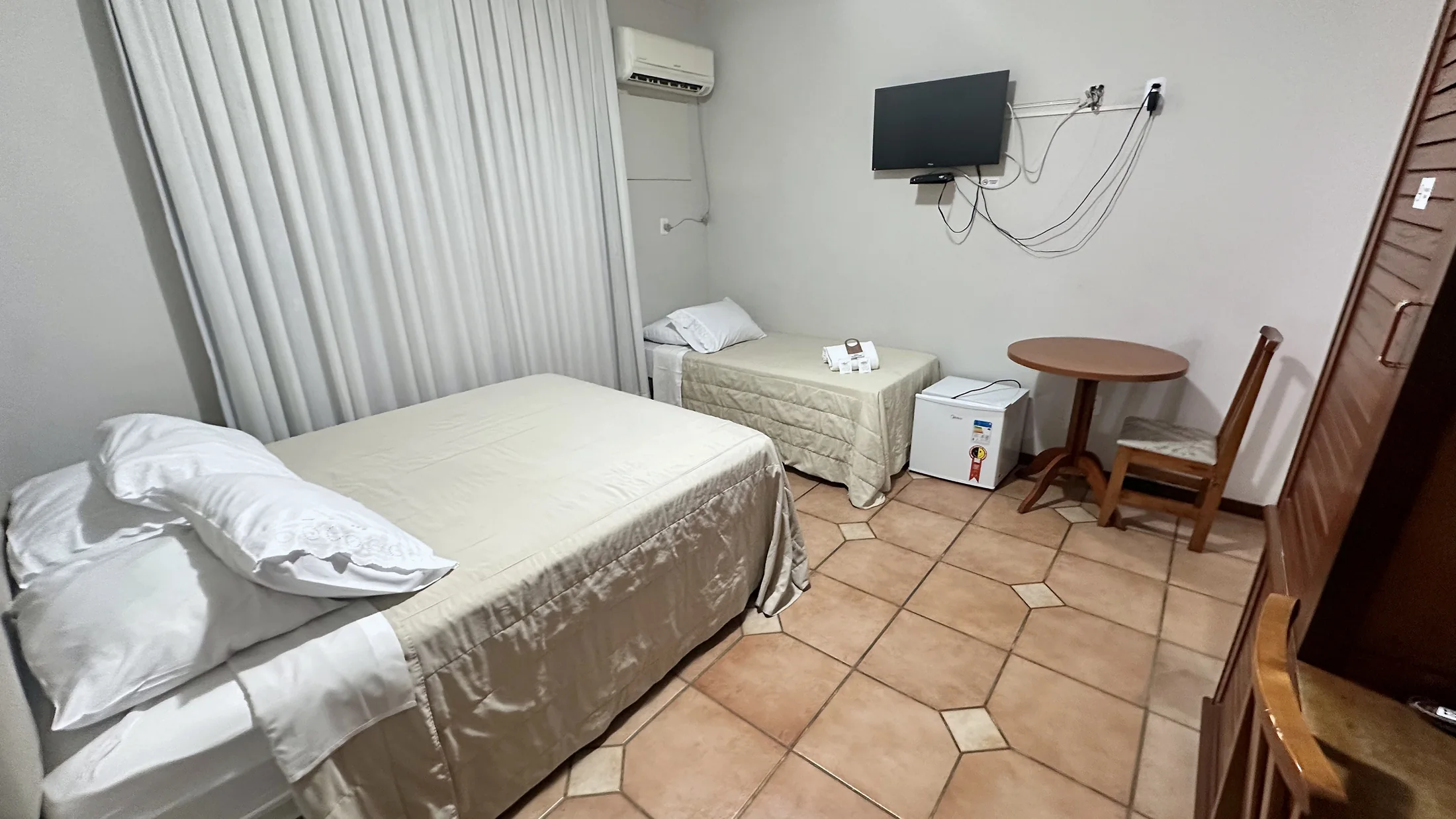Quarto do Hotel Beira Rio com camas, mesa, TV e frigobar