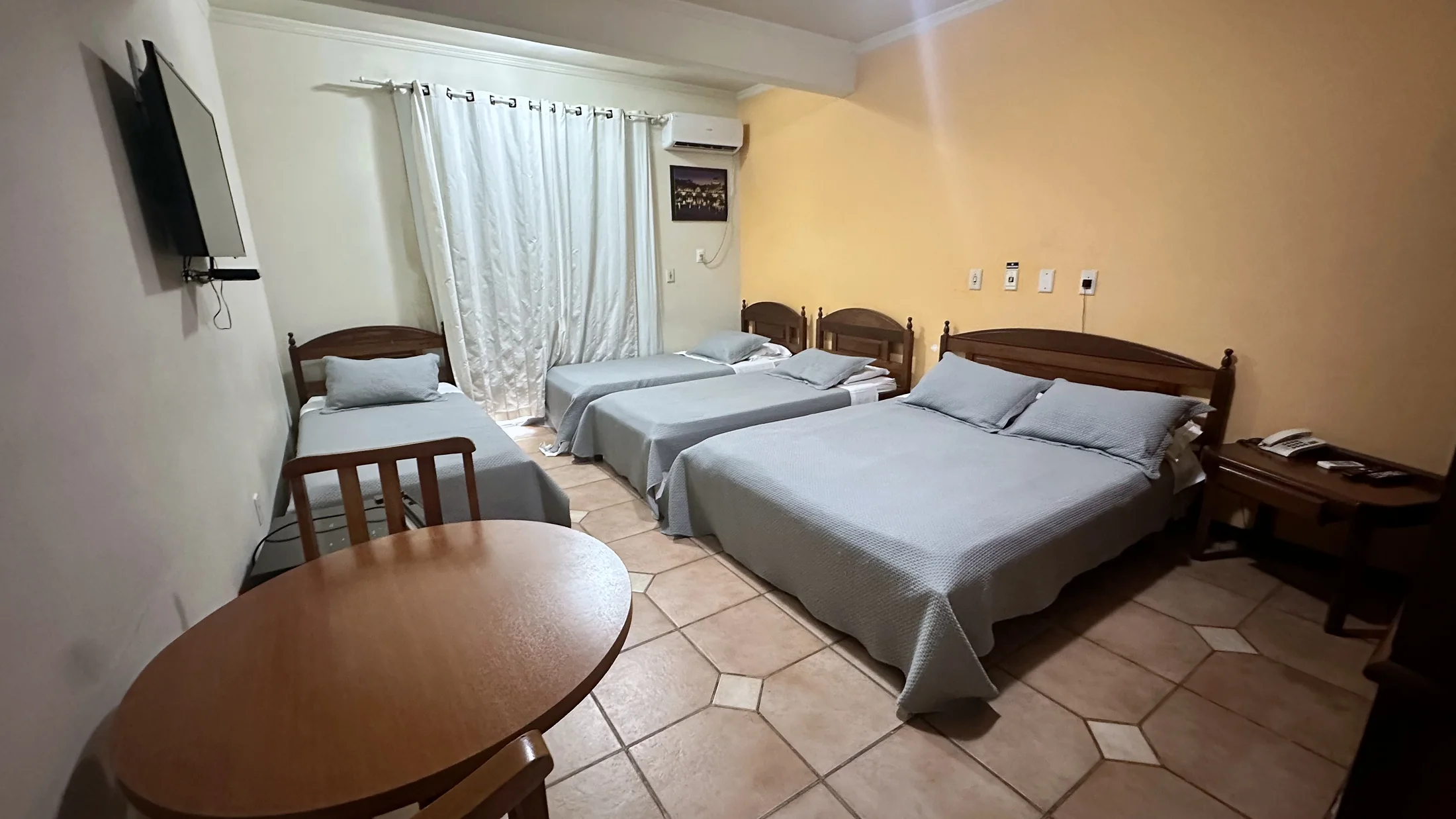 Quarto amplo e real do Hotel Beira Rio com uma cama de casal e camas de solteiro